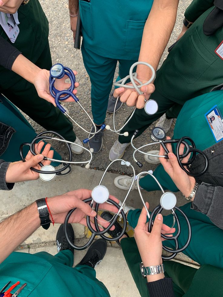 Equipo de médicos en bata verde formando un círculo con sus fonendoscopios